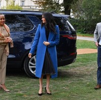 Meghan tampil mencuri atensi dengan mantel biru dari Smythe. Di baliknya, ia memakai atasan hitam sleeveless berbahan kasmir dari Tuxe dan rok lipit Misha Nonoo, rancangan salah satu sahabatnya.Foto: Dok. Getty Images