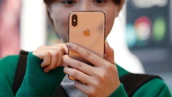 Wanita ini mengamati dengan seksama iPhone XS warna gold yang mungkin akan dibelinya. Foto: Reuters
