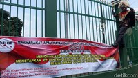 Mereka memasang spanduk di pagar gedung DPR.