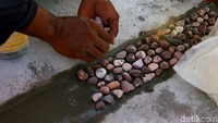 Pekerja tengah memasang bebatuan kerikil untuk menghiasi sisi trotoar jembatan.