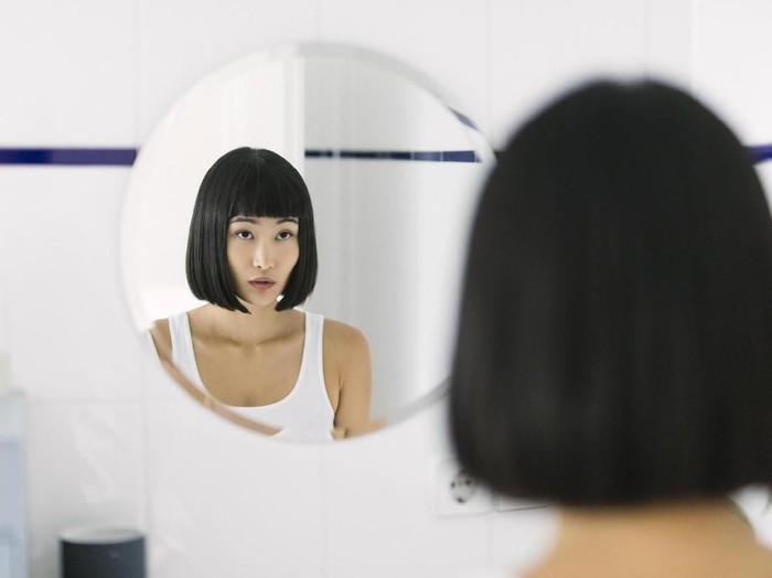 Ilustrasi Wanita Asia Young beautiful Asian woman looking at mirror in the morning.