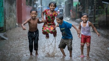 Happiness on a Rainy Day oleh fotografer Bangladesh, Fardin Oyan. Memperlihatkan anak kecil di Bangladesh bergembira meski di tengah hujan dan terancam banjir. Foto: Environmental Photographer Of The Year
