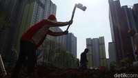 Sejumlah pekerja merapikan taman Wisma Atlet Kemayoran.