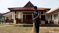 Sebuah bangunan dengan desain ala rumah Betawi yang kental terlihat dibelakang petugas yang sedang membersihkan halaman.