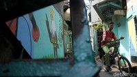 Seorang warga melintas dengan sepedanya di lorong yang bergambar Elang Bondol.