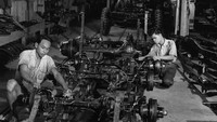 Dua pekerja tampak sibuk merakit sebuah mobil di pabrik otomotif sekitar tahun 1950.  