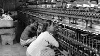 Dua orang wanita tampak sibuk mengawasi mesin pemintal benang ke kumparan agar tak terbelit atau tersangkut di sebuah pabrik garmen di kota Bandung sekitar tahun 1955.   