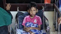 Seorang bocah terpaksa menggunakan kursi roda akibat luka-luka yang dideritanya.