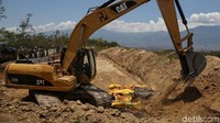 Ekskavator diturunkan untuk memudahkan proses pemakaman.