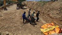 Sebuah ekskavator dikerahkan untuk proses penguburan massal ini. Setelah 18 jenazah itu tersusun tapi, ekskavator pun langsung melakukan penimbunan.