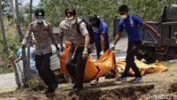 Personel kepolisian membantu menurunkan jenazah.