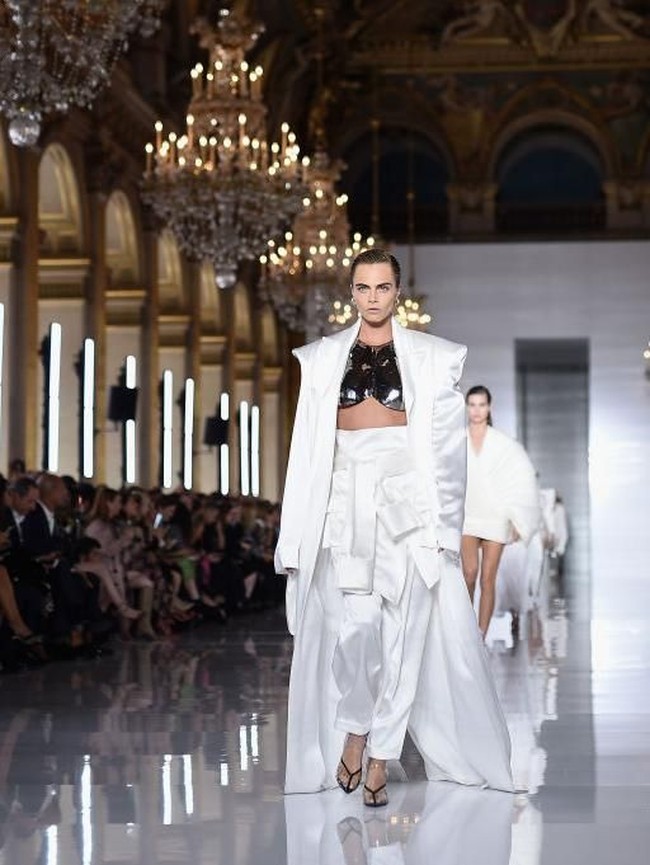Cara menebar pesonanya dalam balutan coat putih bersiluet longgar yang membungkus cropped-top berbahan metal dan celana palazzo bersabuk asimetris. (Foto: Pascal Le Segretain/Getty Images)