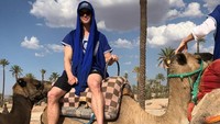 Di Maroko, Chris Hemsworth sempat wisata padang pasir dan naik unta mengenakan kaos biru juga celana pendek hitam (chrishemsworth/Instagram)