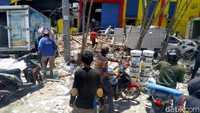 Tampak sejumlah orang membawa banyak kaleng cat hasil mencari barang-barang dari pusat pergudangan di Tondo, Palu.