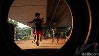 Meski sangat sederhana mereka tampak senang bermain bola di kolong jembatan.