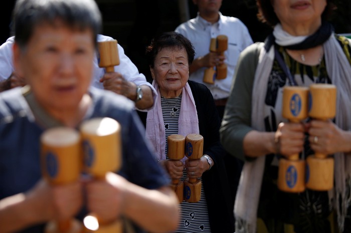 Elderly and middle-aged people exercise with wooden dumbbells during a health promotion event to mark Japans 