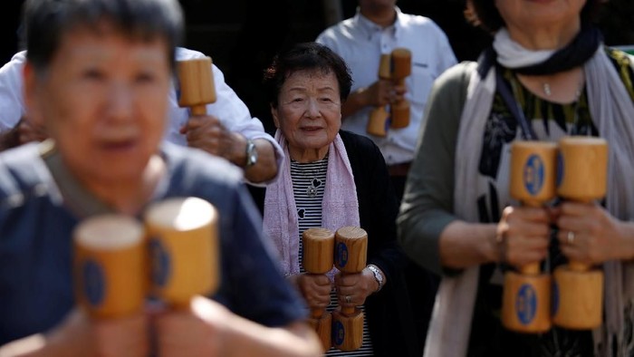 Elderly and middle-aged people exercise with wooden dumbbells during a health promotion event to mark Japans Respect for the Aged Day at a temple in Tokyos Sugamo district, an area popular among the Japanese elderly, September 17, 2018. REUTERS/Issei Kato
