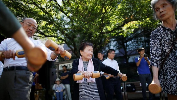 Elderly and middle-aged people exercise with wooden dumbbells during a health promotion event to mark Japans 