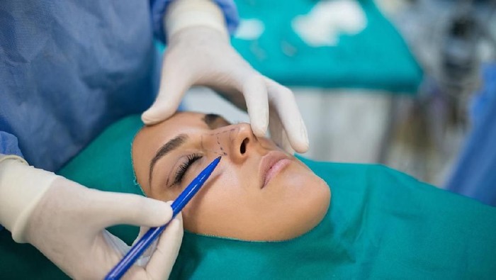 operasi plastik Close-up Of A Surgeon Drawing Perforation Lines On Young Womans Face For Plastic Surgery