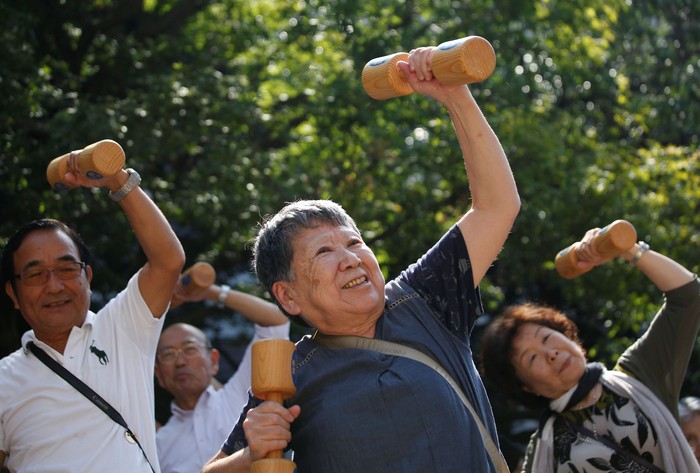 Elderly and middle-aged people exercise with wooden dumbbells during a health promotion event to mark Japans 