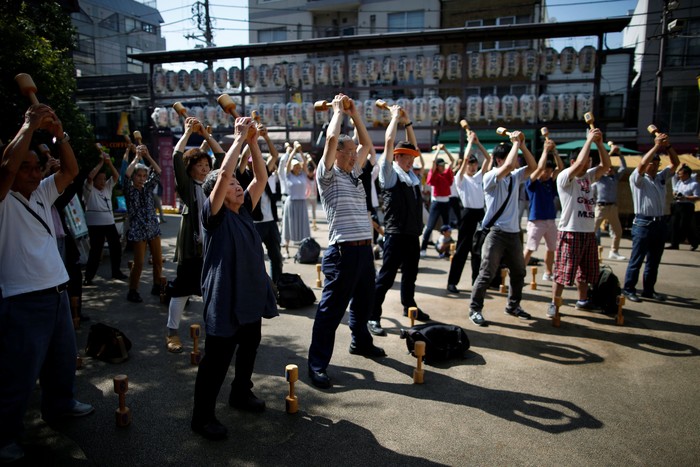 Elderly and middle-aged people exercise with wooden dumbbells during a health promotion event to mark Japans 