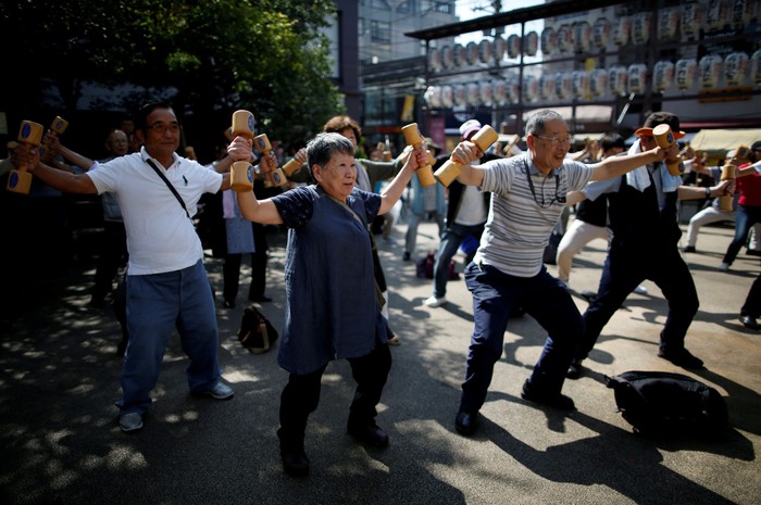 Elderly and middle-aged people exercise with wooden dumbbells during a health promotion event to mark Japans 