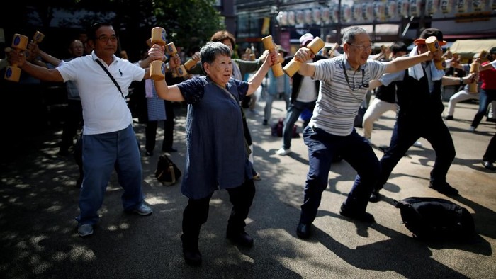 Elderly and middle-aged people exercise with wooden dumbbells during a health promotion event to mark Japans Respect for the Aged Day at a temple in Tokyos Sugamo district, an area popular among the Japanese elderly, September 17, 2018. REUTERS/Issei Kato