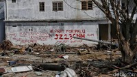 Tembok rumah yang masih kokoh dijadikan tempat mengadu warga dengan menuliskan permintaan bantuan.