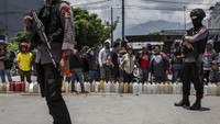 Polisi berjaga di depan warga yang mengantre BBM. Ulet Ifansasti/Getty Images.