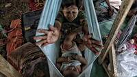 Seorang ibu mencoba menghibur anaknya yang masih balita di bawah tenda darurat.