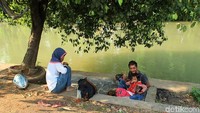 Tak sedikit warga yang asyik menghabiskan siang dengan bersantai di bawah rimbunnya pohon di bantaran sungai Kali Malang (Randy/detikTravel)