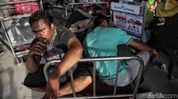 Troli barang digunakan beberapa calon penumpang untuk beristirahat.