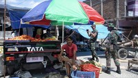 Seorang anggota TNI memotret seorang pedagang bersama anaknya.