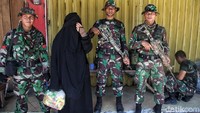 Seorang warga berfoto dengan anggota TNI yang tengah berjaga.