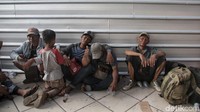 Sebagian calon penumpang menunggu keberangkatan dengan duduk di lantai ruang tunggu bandara.
