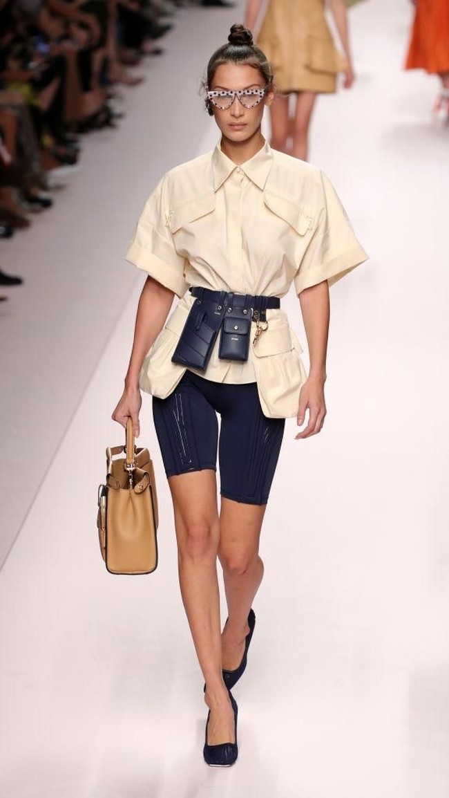 Di peragaan Fendi yang digelar dalam rangkaian Milan Fashion Week, model Bella Hadid muncul dengan blus kuning bersiluet longgar dan celana sepeda biru dongker sebagai bawahan, berikut heels berwarna senada. Tangannya tampak menenteng handbag kulit coklat yang feminin. Sementara tas kecil seperti wadah ponsel menggantung di sabuk kemeja. Inikah gaya ideal ke kantor di masa mendatang? (Foto: Getty Images)