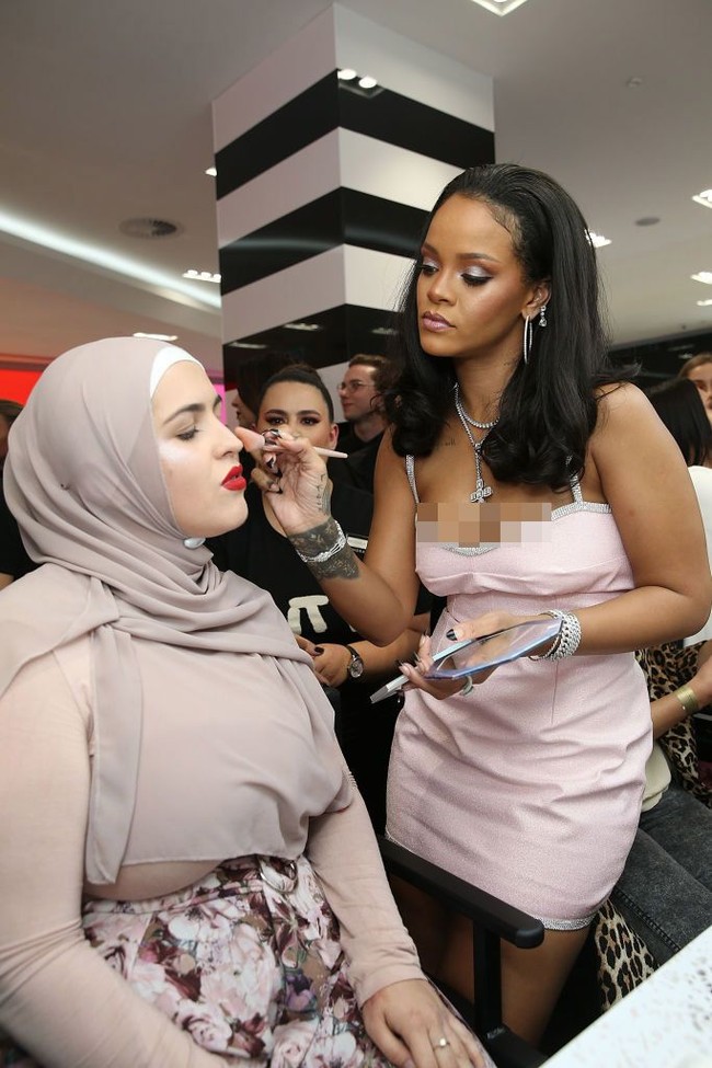 Rihanna tampak serius merias wajah seorang wanita layaknya makeup artist profesional. Foto: Getty Images