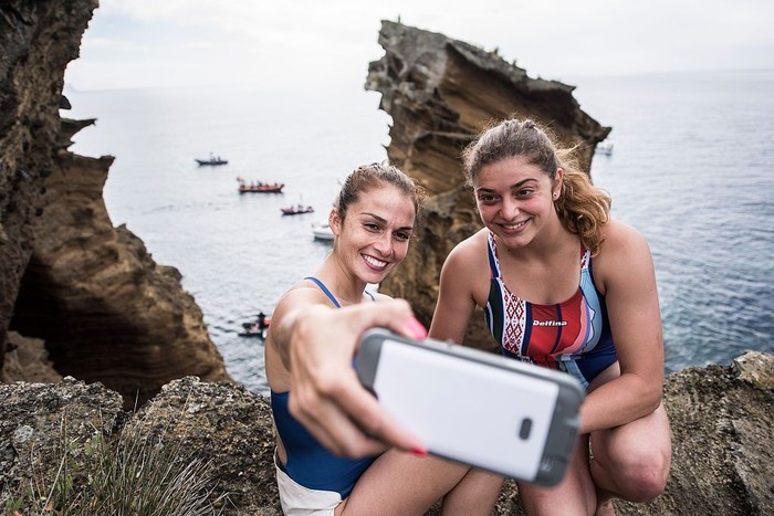 AZORES, PORTUGAL - JULY 07:  (EDITORIAL USE ONLY) In this handout image provided by Red Bull, Jacqueline Valente (L) of Brazil takes a selfie with Yana Nestsiarava of Belarus on the cliffs at Islet Franca do Campo during the first training session prior to the third stop of the Red Bull Cliff Diving World Series, Sao Miguel, Azores, Portugal on July 7th 2016. (Photo by Dean Treml/Red Bull via Getty Images)