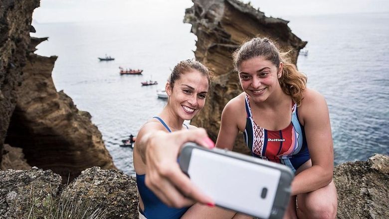 AZORES, PORTUGAL - JULY 07:  (EDITORIAL USE ONLY) In this handout image provided by Red Bull, Jacqueline Valente (L) of Brazil takes a selfie with Yana Nestsiarava of Belarus on the cliffs at Islet Franca do Campo during the first training session prior to the third stop of the Red Bull Cliff Diving World Series, Sao Miguel, Azores, Portugal on July 7th 2016. (Photo by Dean Treml/Red Bull via Getty Images)