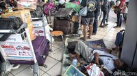 Sebagian calon penumpang menunggu kepastian keberangkatan dengan tiduran di lantai ruang tunggu. Dia tidur dengan beralaskan tikar.