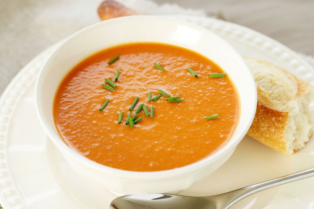 A bowl of hot butternut soup with baguette. Horizontal.