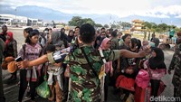 Prajurit TNI meminta para korban gempa untuk tenang sebelum memasuki pesawat.