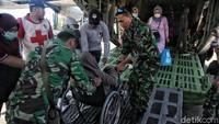 Prajurit TNI membantu mendorong kursi roda menuju pesawat Hercules.