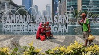 Warga berfoto-foto dengan latar belakang air mancur Bundaran HI.