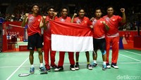 Tim bulutangkis beregu putra Indonesia membentangkan bendera merah putih di tengah lapangan.