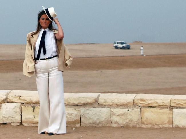 Melania Trump menyambangi Piramida Spinx di sela turnya ke Mesir. Ia memakai blus putih Chanel yang berdasikan pita dengan luaran blazer off-white Ralph Lauren. Untuk bawahan, celana palazzo putih jadi andalan. Gayanya turut dipermanis dengan topi fendora berhiaskan korsase. Tidak ketinggalan sepasang heels Chanel untuk menopang kakinya. (Foto: REUTERS/Carlo Allegri)