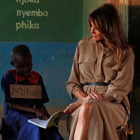 Dari Ghana, tur Melania berlanjut ke Malawi di mana ia bertemu dengan murid-murid SD setempat. Shirt dress coklat bergaya safari dengan sabuk tali yang manis dan suede heels oranye Manolo Blahnik jadi andalan sang mantan model itu. (Foto: Reuters)