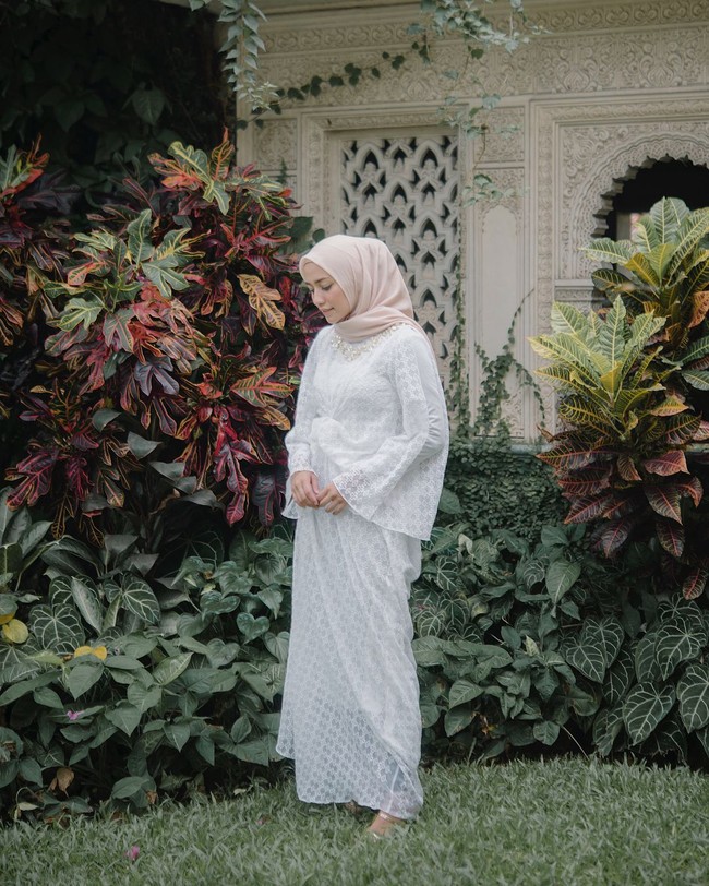 Memakai kaftan ke acara pernikahan, kenapa tidak? Mega Iskanti memilih kaftan berbahan lace dan berwarna putih. Potongannya yang unik membuatnya tampak cantik. Foto: Instagram/Megaiskanti
