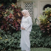 Memakai kaftan ke acara pernikahan, kenapa tidak? Mega Iskanti memilih kaftan berbahan lace dan berwarna putih. Potongannya yang unik membuatnya tampak cantik. Foto: Instagram/Megaiskanti
