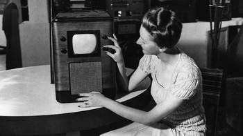 Seorang perempuan mendemonstrasikan sebuah TV mungil di tahun 1938. Bentuknya lebih mirip case CPU saat ini ya? (Foto: Central Press/Getty Images)